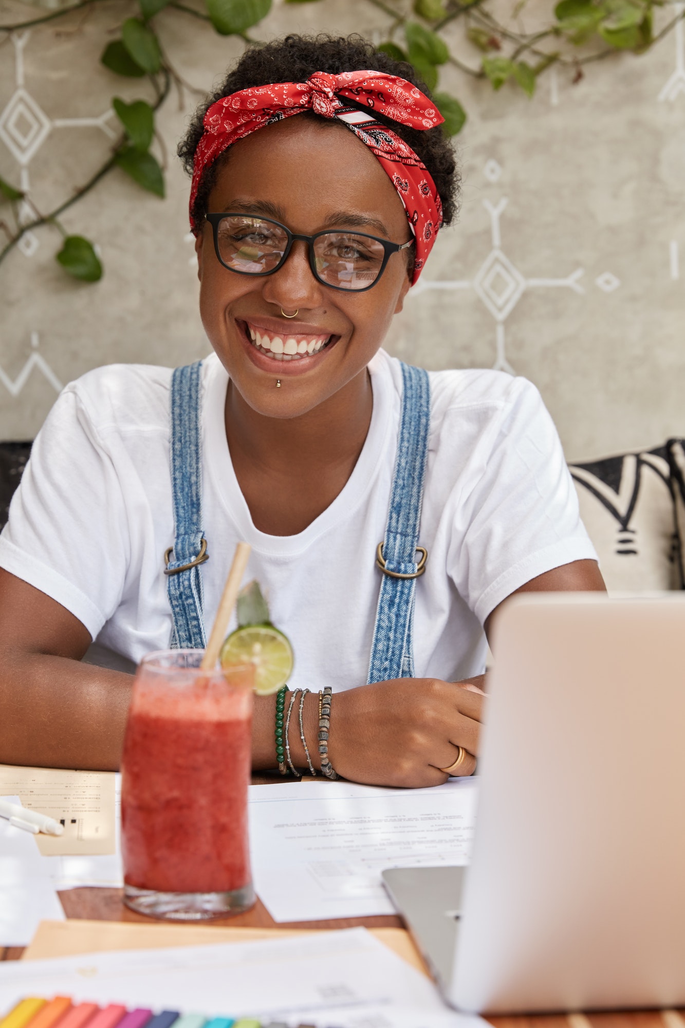 portrait of cheerful black student does homework in cozy coffee shop uses laptop computer for writi